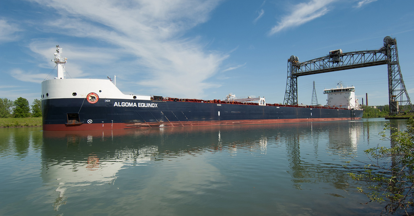 Buque de carga "Algoma Equinox" pasando bajo un puente levadizo en un día tranquilo.