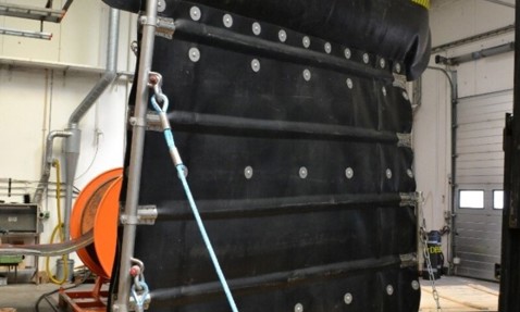 DESMI oil spill recovery boom in a workshop setting, with secured ropes.