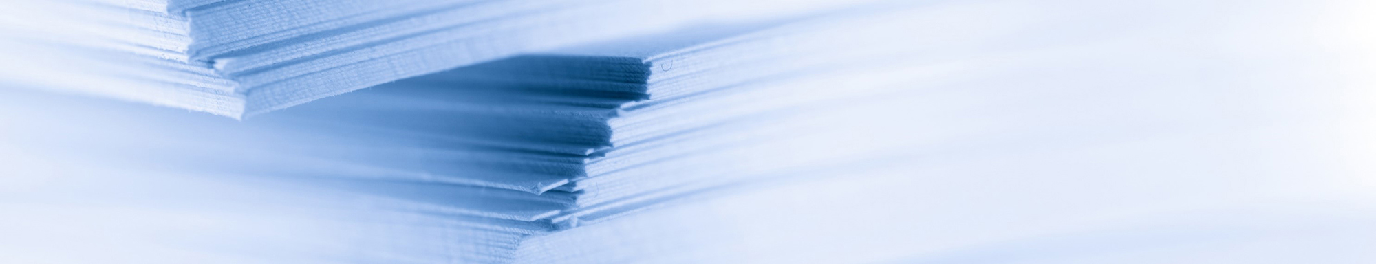 Zbliżenie ułożonych arkuszy papieru z delikatnym niebieskim odcieniem.