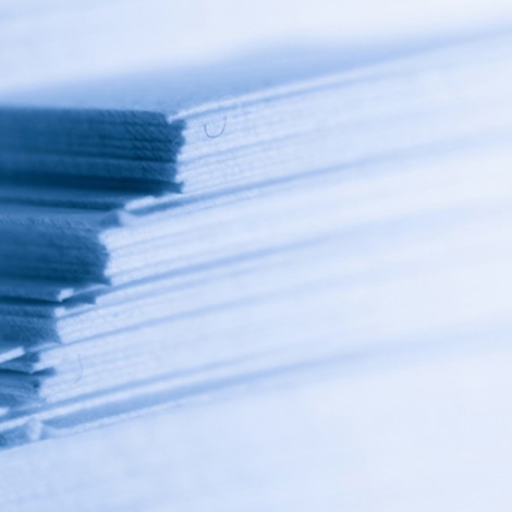 Zbliżenie ułożonych arkuszy papieru z delikatnym niebieskim odcieniem.