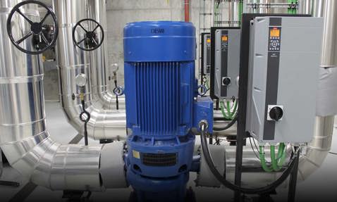 Blue DESMI pump with control panels and pipes in an industrial facility.