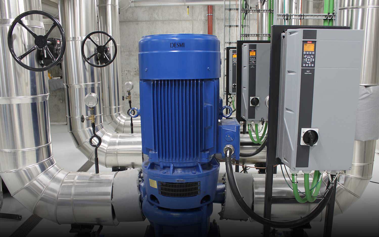 Blue DESMI pump with control panels and pipes in an industrial facility.