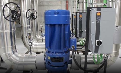 Blue DESMI pump with control panels and pipes in an industrial facility.