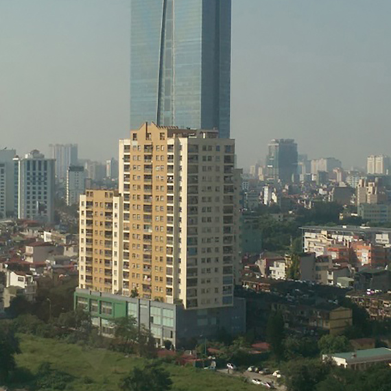 Tall skyscraper with "Lotte" sign, surrounded by smaller buildings, near a river.