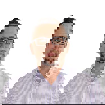 Man with glasses and goatee wearing a striped shirt against a white background.