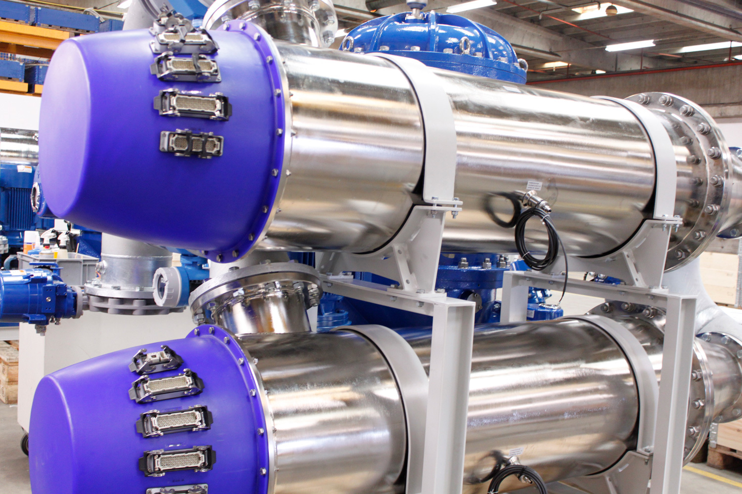 Industrial fluid handling equipment with metallic cylinders and blue end caps.