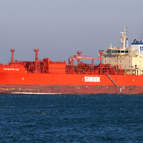 Red LPG tanker "Navigator Leo" sailing on the ocean under clear skies.