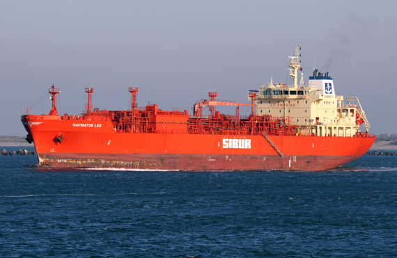 Red LPG tanker "Navigator Leo" sailing on the ocean under clear skies.