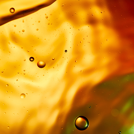 Close-up of vibrant orange liquid with bubbles, creating an abstract pattern.