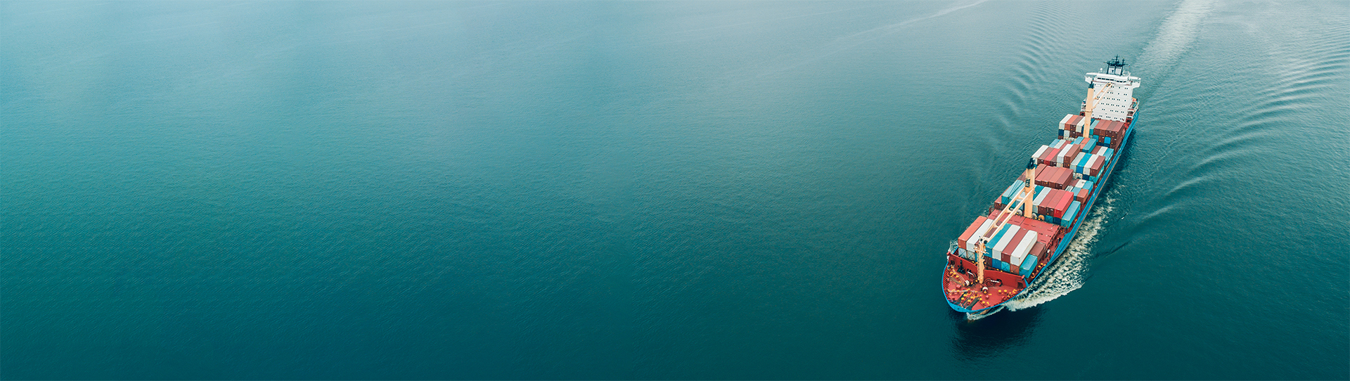 Lastfartyg som transporterar containrar seglar genom lugna blå havsvatten.