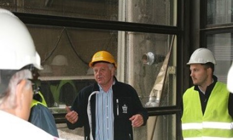 People wearing safety gear in an industrial setting during a discussion.