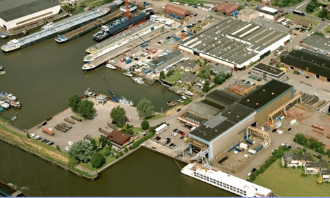 Aerial view of a shipyard with docked boats and industrial buildings.