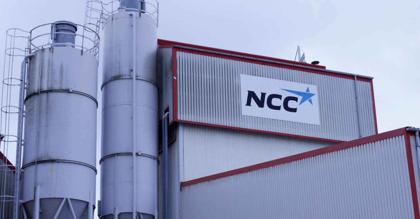 Industrial building with silos and NCC logo on the facade.