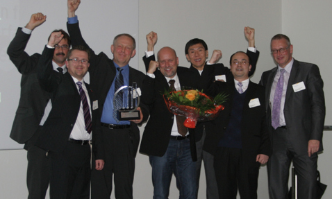 Group of men celebrating with a trophy and flowers, raising their fists.
