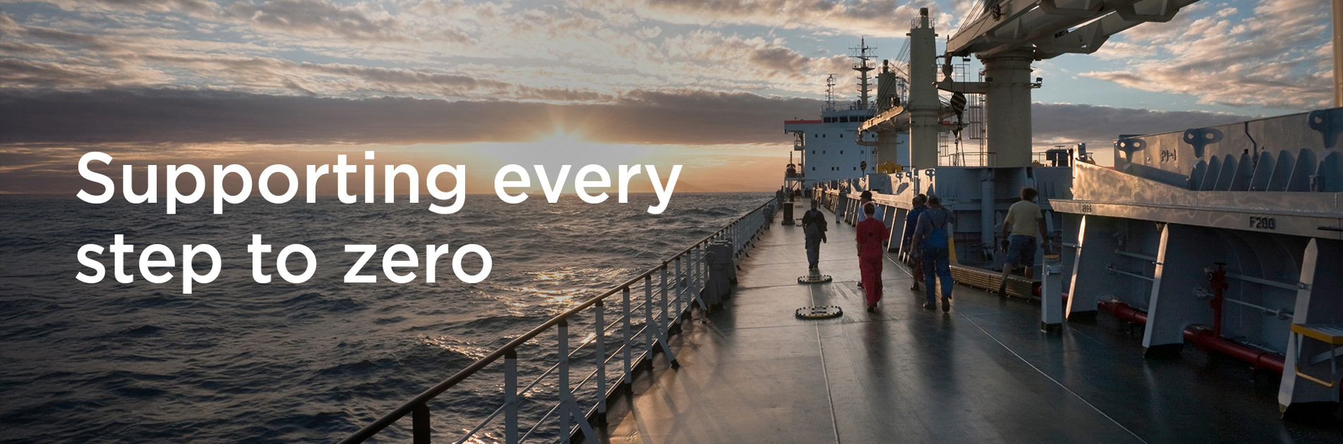 People walking on a ship deck at sunset, with text "Supporting every step to zero."