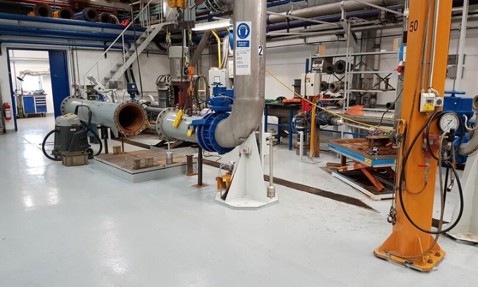 Industrial facility with large metal pipes and machinery for fluid handling processes.