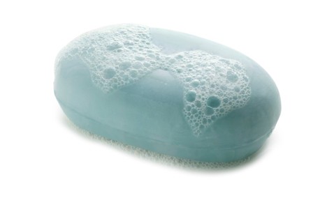 Light blue soap bar with bubbles on top, isolated on a white background.