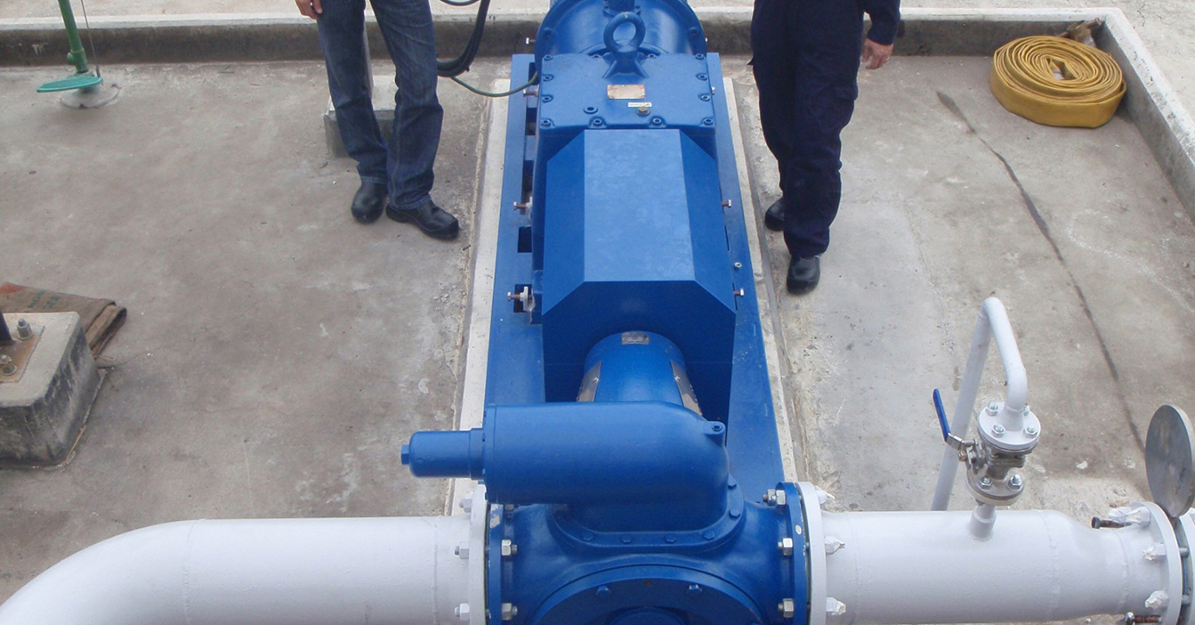 Two workers with a DESMI ROTAN pump for fluid handling on an industrial site.