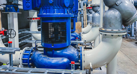 Blue industrial pump system with interconnected pipes in a fluid handling facility.
